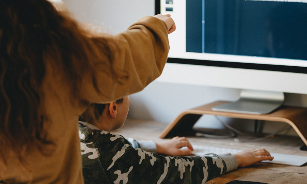 Parent points out something on computer screen to child